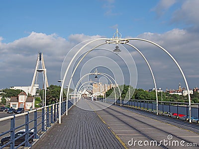 The historic pier in southport merseyside with people walking towards the town and the suspension bridge and buildings visible beh Editorial Stock Photo