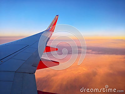 Southwest Airlines flight over clouds at sunset. Wing view Editorial Stock Photo