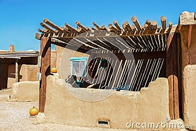 Southwestern US Adobe dwelling with pole ramada sunshade over patio and painted details in turquoise with pumpkins sitting around Stock Photo