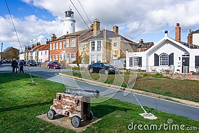Southwold`s iconic lighthouse seen behind houses with cannon in foreground in Southwold, Suffolk, UK Editorial Stock Photo