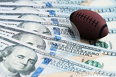 Souvenir ball for playing rugby or American football on US banknotes. The concept of corruption or sports betting. Stock Photo