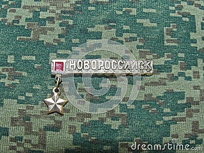 Soviet metal badge with the image of a gold star and the inscription `Novorossiysk`, from the series `Hero cities of the USSR` Editorial Stock Photo