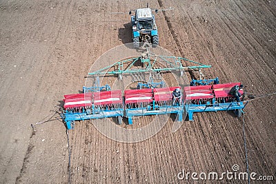 Sowing campaign. The tractor sows the field with grain. There are two seeders sitting on the planter. Shooting from a drone. Copy Stock Photo