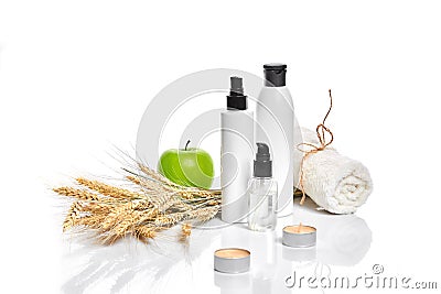 Spa cosmetics, jar of cream, oil with wheat, white cosmetic bottles with apple and wheat towel, candle, soap isolated on Stock Photo