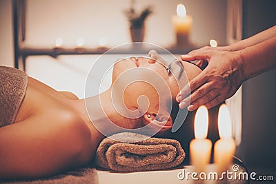 Spa facial massage. Brunette woman enjoying relaxing face massage Stock Photo