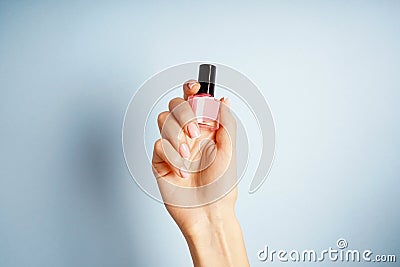 Spa and Manicure concept. Female hand with stylish french manicure, holds a bottle with nail polish Stock Photo