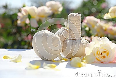 Spa massage herbal bags, rose and petals on white table in garden. Harmony and zen Stock Photo