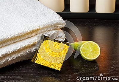 Spa massage with towel stacked white candles sea salt and lime Stock Photo