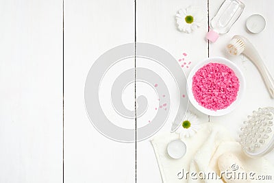 Spa setting with sea salt in bowl, towel, massage tool, chamomile flowers, candles on woode background, top view. Wellness Stock Photo