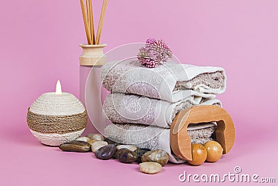 Spa essentials, aroma sticks stones, towels and a plant on a pink background Stock Photo