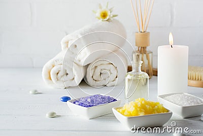 Spa still life with towel,white lily, sea salt, bath oil, sugar body scrub, massage brush Stock Photo