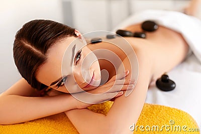 Spa Stone Massage. Young Woman Have Hot Stone Massage Treatments Stock Photo