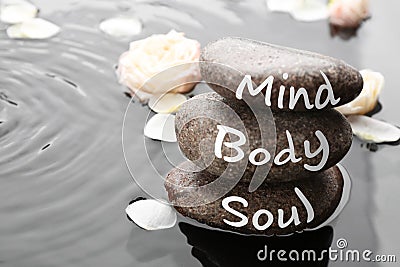 Spa stones with words Mind, Body, Soul and rose petals in water. Zen lifestyle Stock Photo