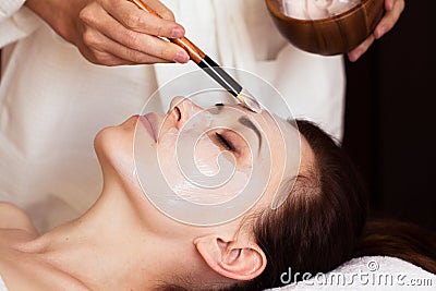 Spa treatment. Beautiful woman with facial mask at beauty salon. Stock Photo