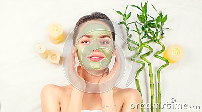 Spa Woman applying Facial green clay Mask. Beauty Treatments. Close-up portrait of beautiful girl in spa salon Stock Photo