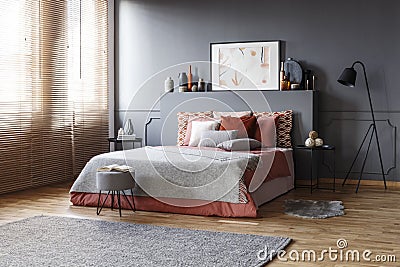 Spacious bedroom interior with a comfy bed, pillows, lamp, paint Stock Photo