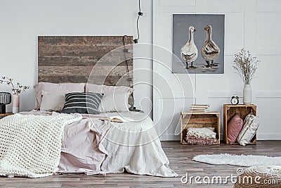 Spacious, feminine bedroom interior with rustic furniture, white walls, wooden crates and oil painting of animals. Real photo Stock Photo