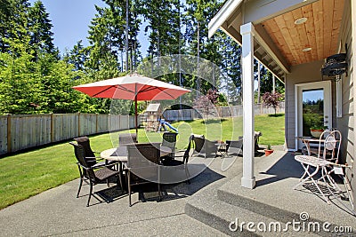 Spacious fenced backyard area with patio table and play set for kids Stock Photo