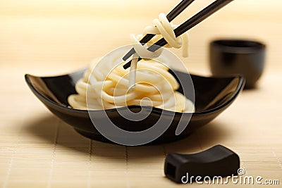 Spaghetti macaroni in black ceramic plate with chopsticks at light bamboo mat Stock Photo