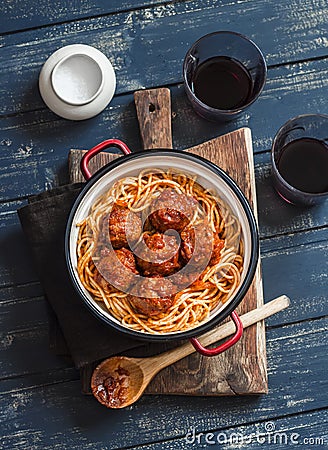 Spaghetti and meatballs in tomato sauce and two glasses with red wine on wooden rustic board. Stock Photo