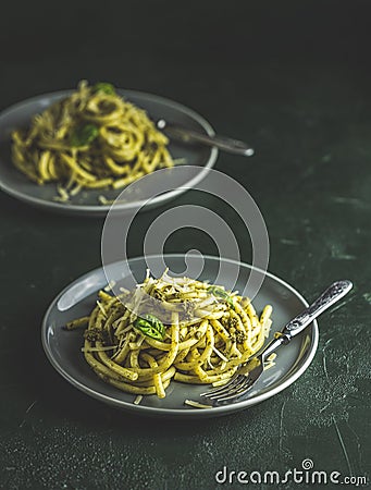 Spaghetti pasta bucatini with pesto sauce and parmesan. Italian traditional perciatelli pasta by genovese pesto sauce in two gray Stock Photo