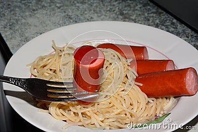 Spaghetti and sausage on a plate. Ketchup on sausages close up Stock Photo