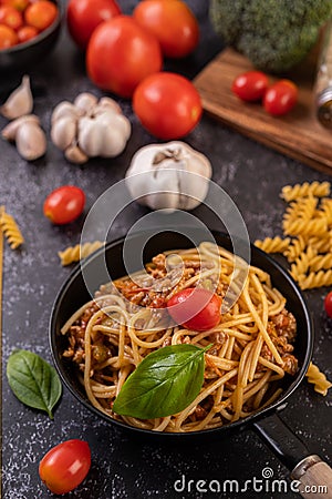 Spaghetti sauteed in a pan-fried with tomatoes and basil Stock Photo