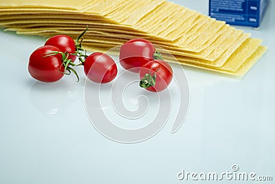 Tomatoes with lasagna on white reflexive glass Stock Photo