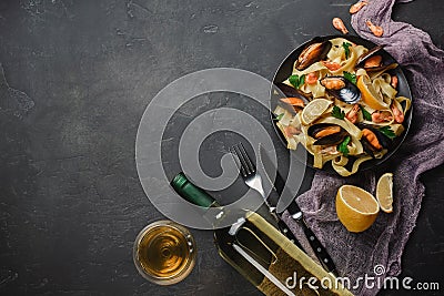 Spaghetti vongole, Italian seafood pasta with clams and mussels, in plate with herbs and glass of white wine on rustic stone Stock Photo