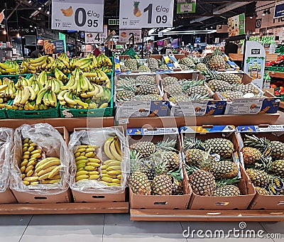 Large fruit section with bananas and pineapples in the foreground for sale Editorial Stock Photo