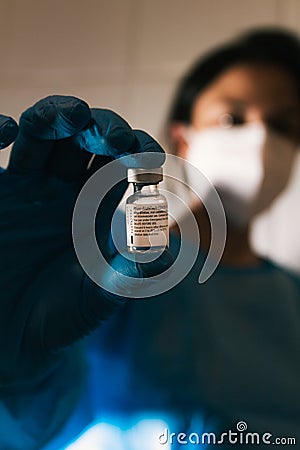 Spain - January 26 2021 Close up picture of an empty phial of Pfizer COVID 19 vaccine hold by a nurse wearing sanitary gloves Editorial Stock Photo
