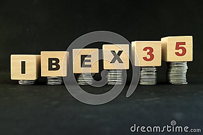 Spain stock market economy growth and recovery concept. IBEX 35 index in wooden blocks with increasing stack of coins in black bac Stock Photo