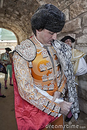 Spainish bullfighter Jose Manuel Montoliu with orange dress and silver putting itself the walk cape before initiating the Editorial Stock Photo