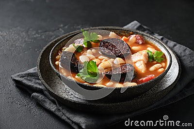 Spanish asturiana fabada with chorizo and morcilla on black background. Stock Photo