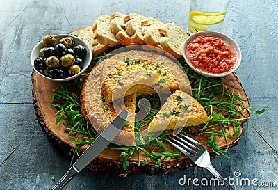 Spanish classic tortilla with potatoes, olives, tomatoes, rucola, bread and herbs. Stock Photo