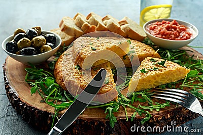 Spanish classic tortilla with potatoes, olives, tomatoes, rucola, bread and herbs. Stock Photo