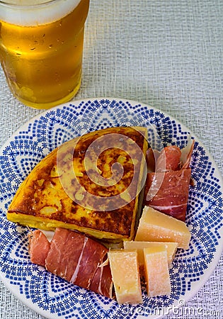 Spanish food and drink, glass of fresh beer and portion of potato omelette tortilla de patatas with onion served with cheese and Stock Photo