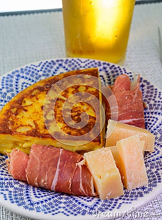 Spanish food and drink, glass of fresh beer and portion of potato omelette tortilla de patatas with onion served with cheese and Stock Photo