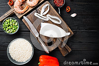 Spanish seafood paella ingredients, rice,prawns, mussels, peas over black wood table, flat lay with copy space Stock Photo