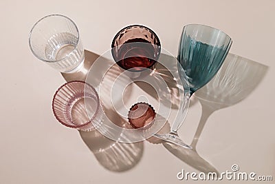Sparcling glasses with long harsh shadows on biege background. Summer still life concept. Stock Photo