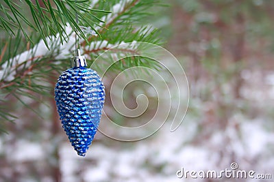 Sparkling blue christmas tree toy cone on a pine branch in a winter snowy forest. Stock Photo