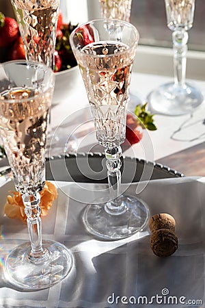 Sparkling rose wine in beautiful crystal flute glasses with bright sunshine streaming in. Stock Photo