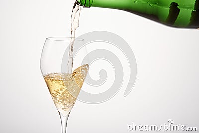 Sparkling wine pours from green bottleneck, creates bubbles. Stock Photo