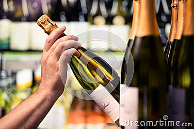 Sparkling wine from shelf of alcohol store. Bottle in hand. Liquor shop. Prosecco or champagne display in spirits market. Stock Photo