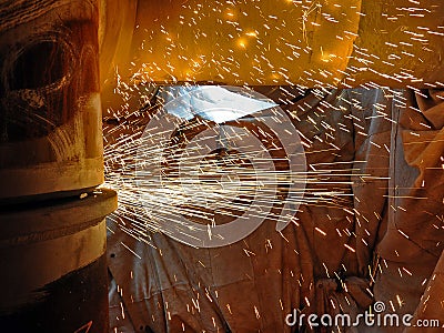 Sparks generated by angle grinder inside work area. Stock Photo