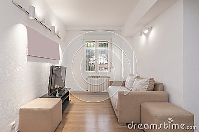 Sparsely furnished apartment with sofas that need to be upholstered next to a barred window Stock Photo