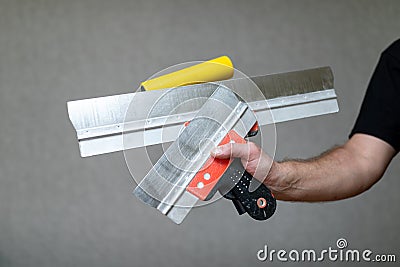 Spatulas in the hand of the master. Home repair tools in the hand of a house painter Stock Photo