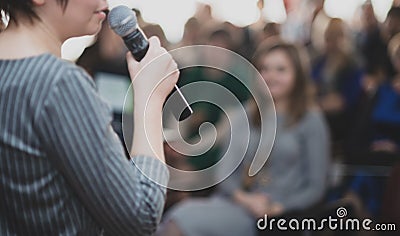 The speaker speaks with a microphone in front of a group of people. Photo is blurry Editorial Stock Photo