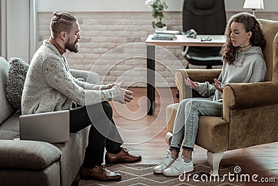 Professional bearded counselor speaking with teenage girl Stock Photo