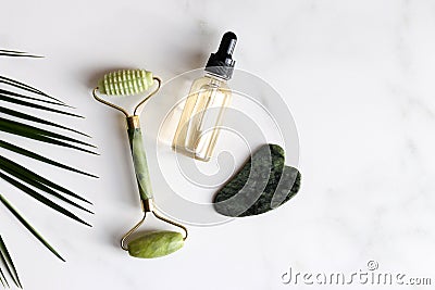 Special devices for Gua Sha. Jade face roller, stone for massage and essential oil on marble table.Traditional Chinese Stock Photo